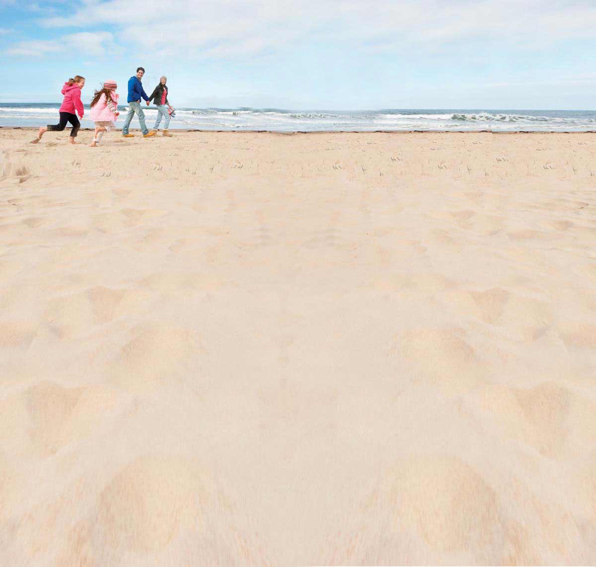 Gezin wandelt over een breed Noordzeestrand in Zeeland